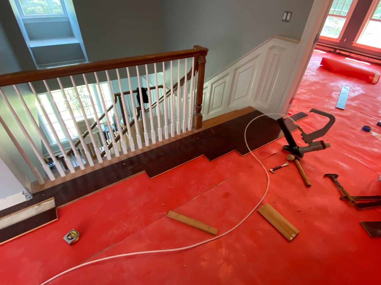 Hardwood flooring being installed along a stair landing with a flooring nailer