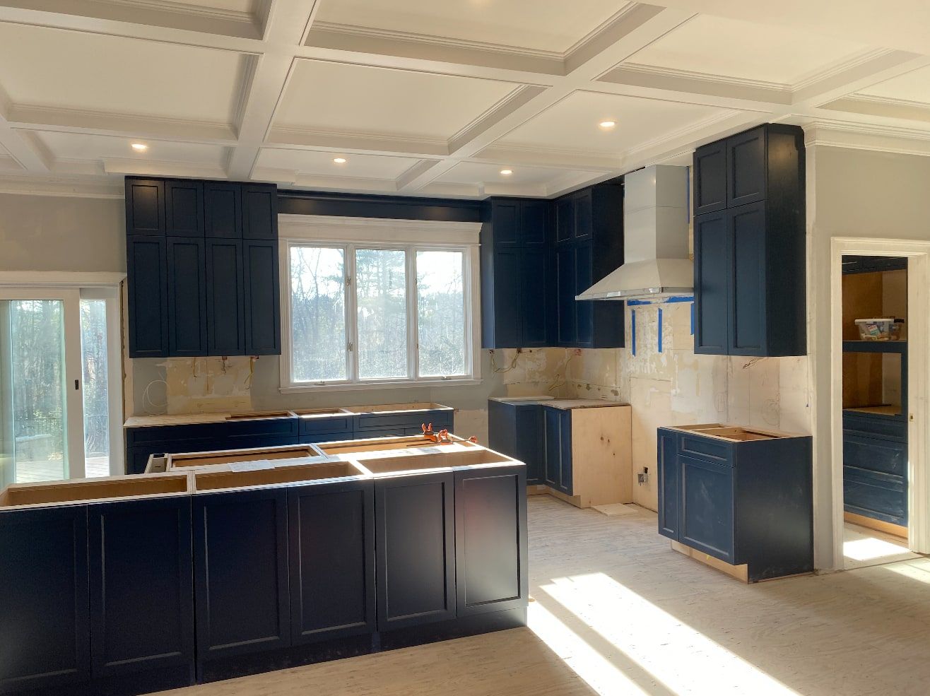 Navy shaker kitchen cabinets installed under a coffered ceiling