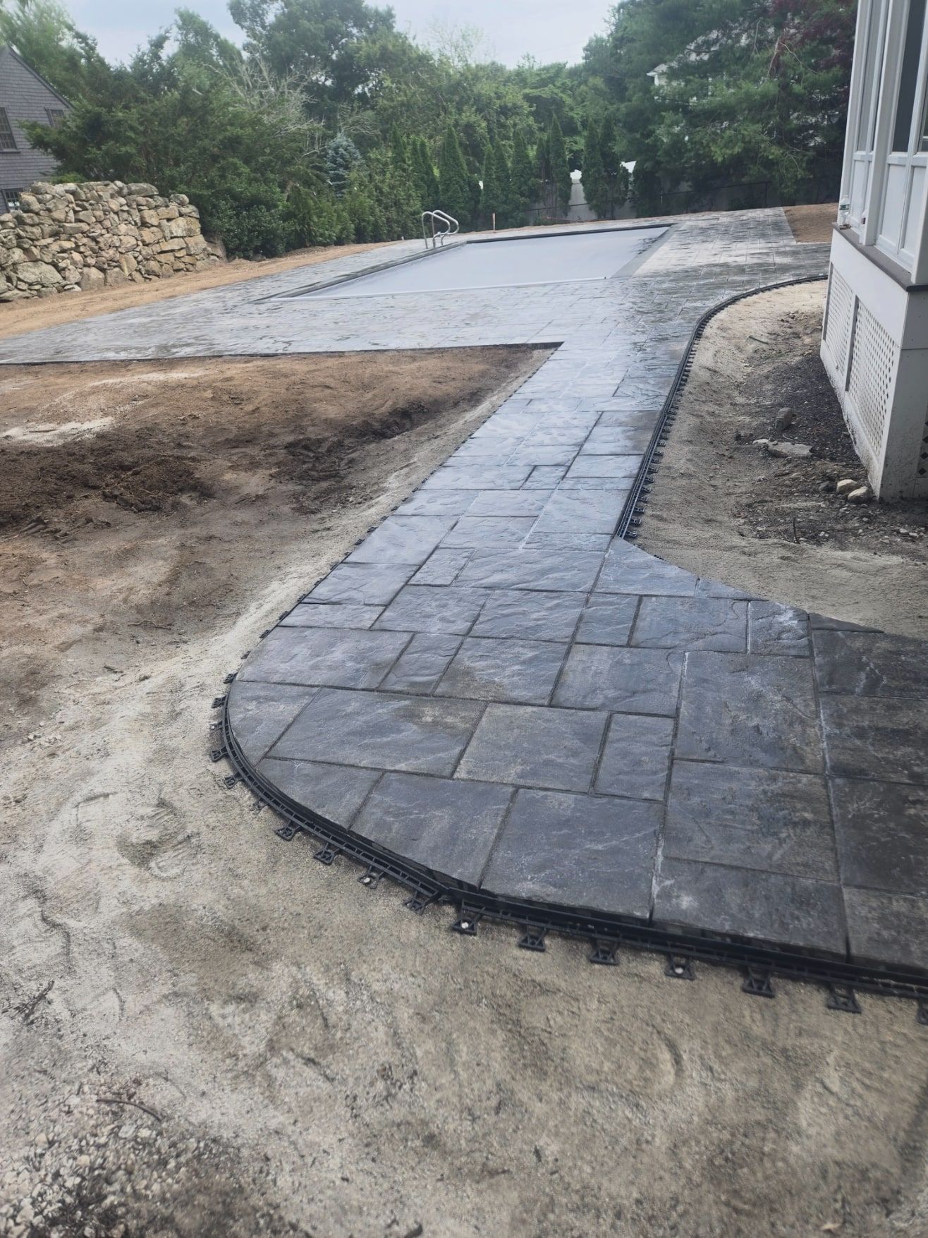 Curved paver walkway leading from the house to a paver pool patio